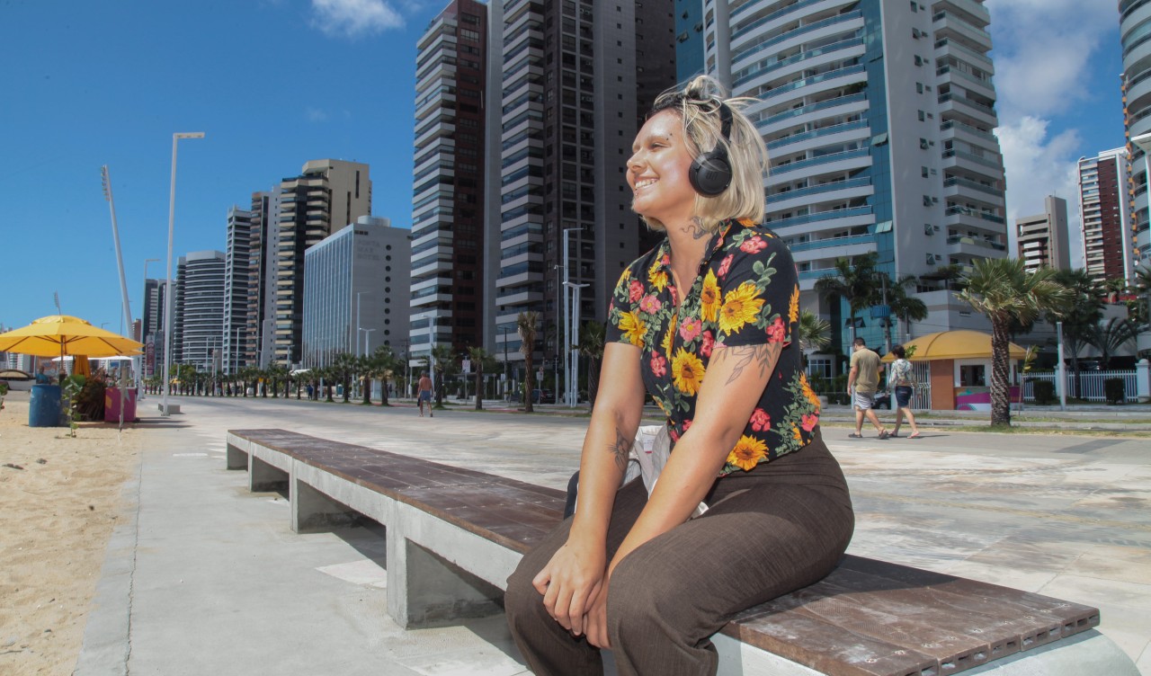 mulher sentada num banco da beira-mar